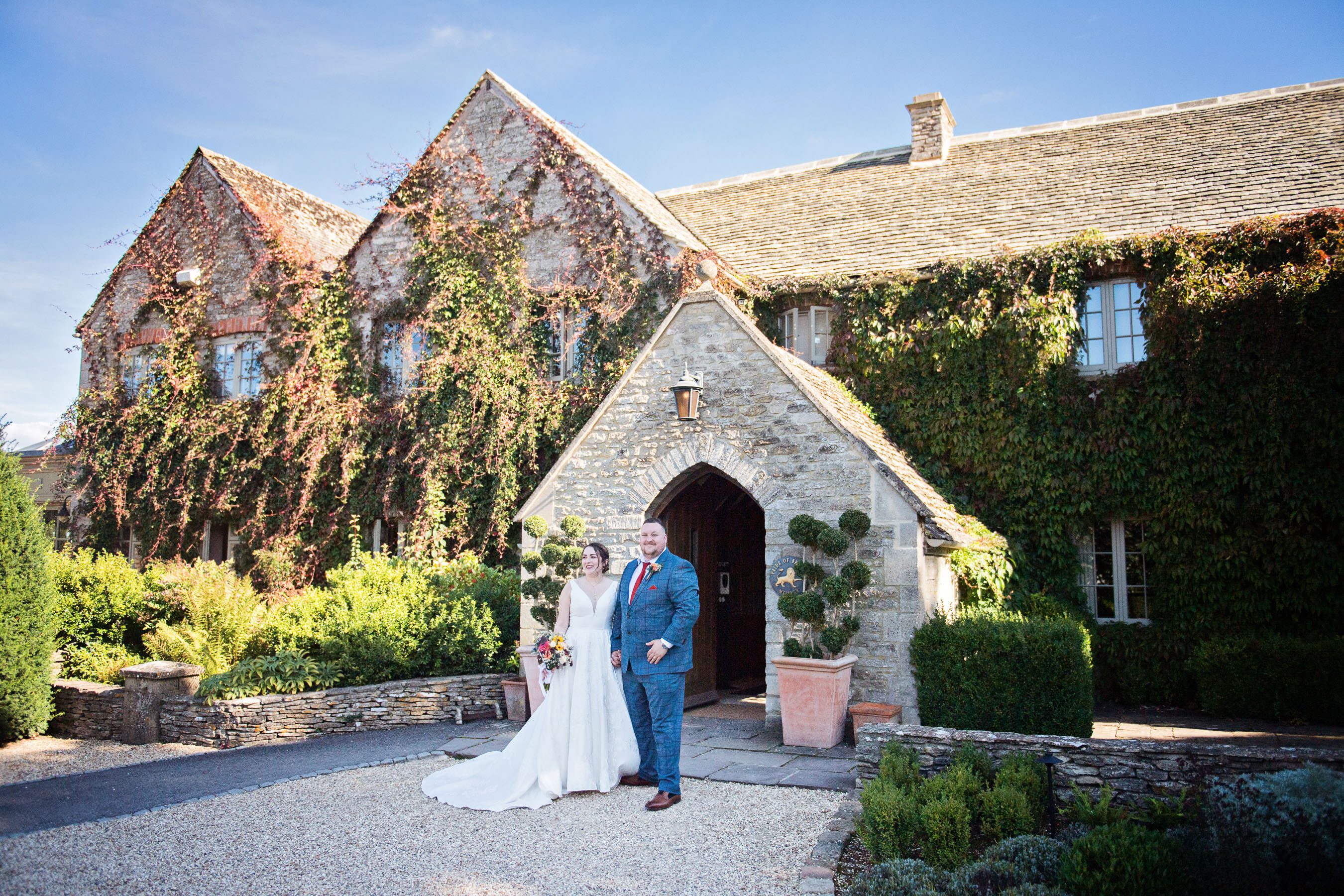 Bride and groom stand out the front of Calcot Manor House.