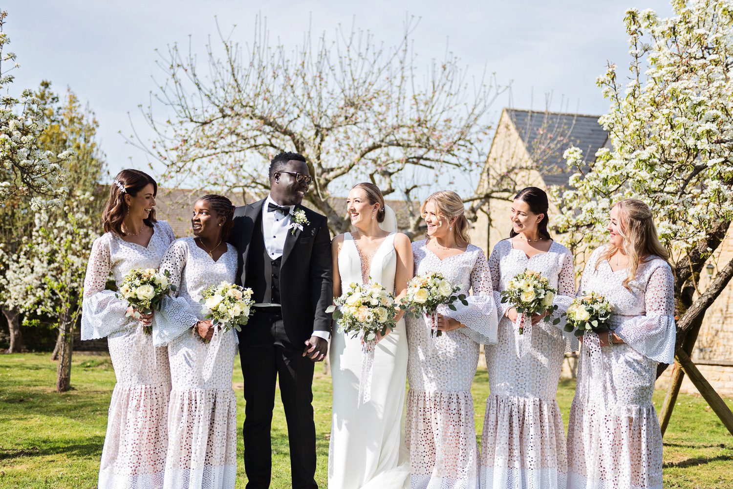 Worton Hall Wedding 0034 Bridesmaid and bride and groom stand in front of blossoming tree's at Worton Hall.